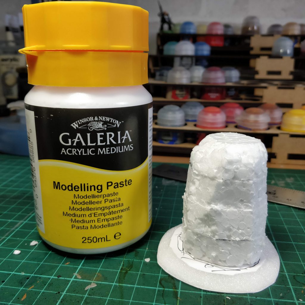 A pot of modelling paste next to a constructed foam standing stone