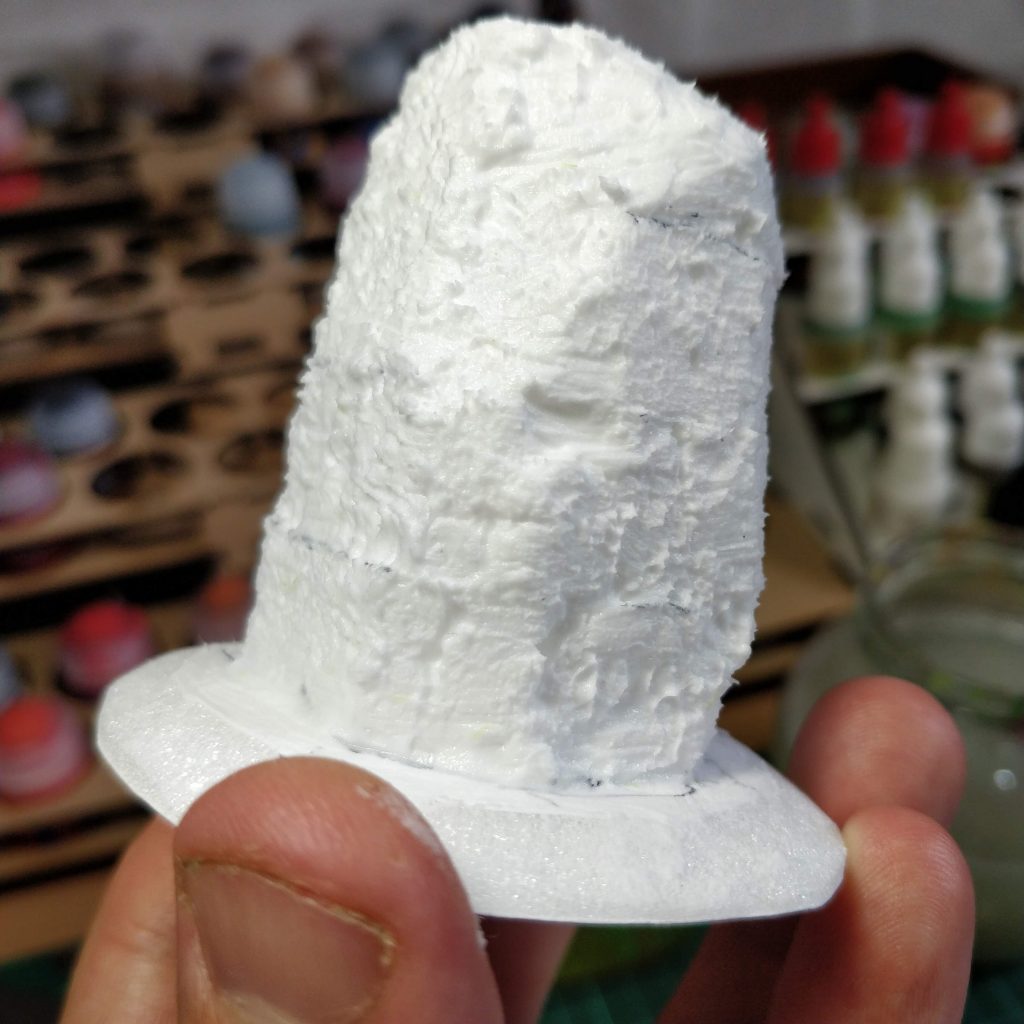 A standing stone with a stippled texture applied to the modelling paste